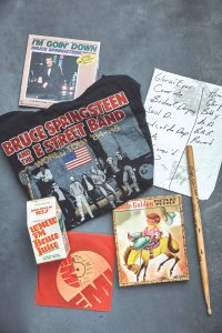 Clockwise from top left: A 45-rpm single of 1985’s “I’m Goin’ Down” from Japan; an undated set list in Springsteen’s handwriting; a drumstick, signed by Max Weinberg, that was among the items donated by the estate of Obediah “Obie” Dziedzic, Springsteen’s former assistant (it reads: “1st Day John Eddie Albany, July 22 1985, For Obie with all my love, Max”); a puzzle based on the 1950 book, Brave Cowboy Bill, which in part inspired Springsteen to write the 2014 children’s book, Outlaw Pete; the single “Born to Run” featuring The Hollies’ Allan Clarke on vocals (Clarke was the first to record Springsteen’s anthem, but the Springsteen version was released first); WNEW-FM used to play a morning block of Springsteen music which the station called the “Bruce Juice” segment; a T-shirt from the Born in the U.S.A. Tour.