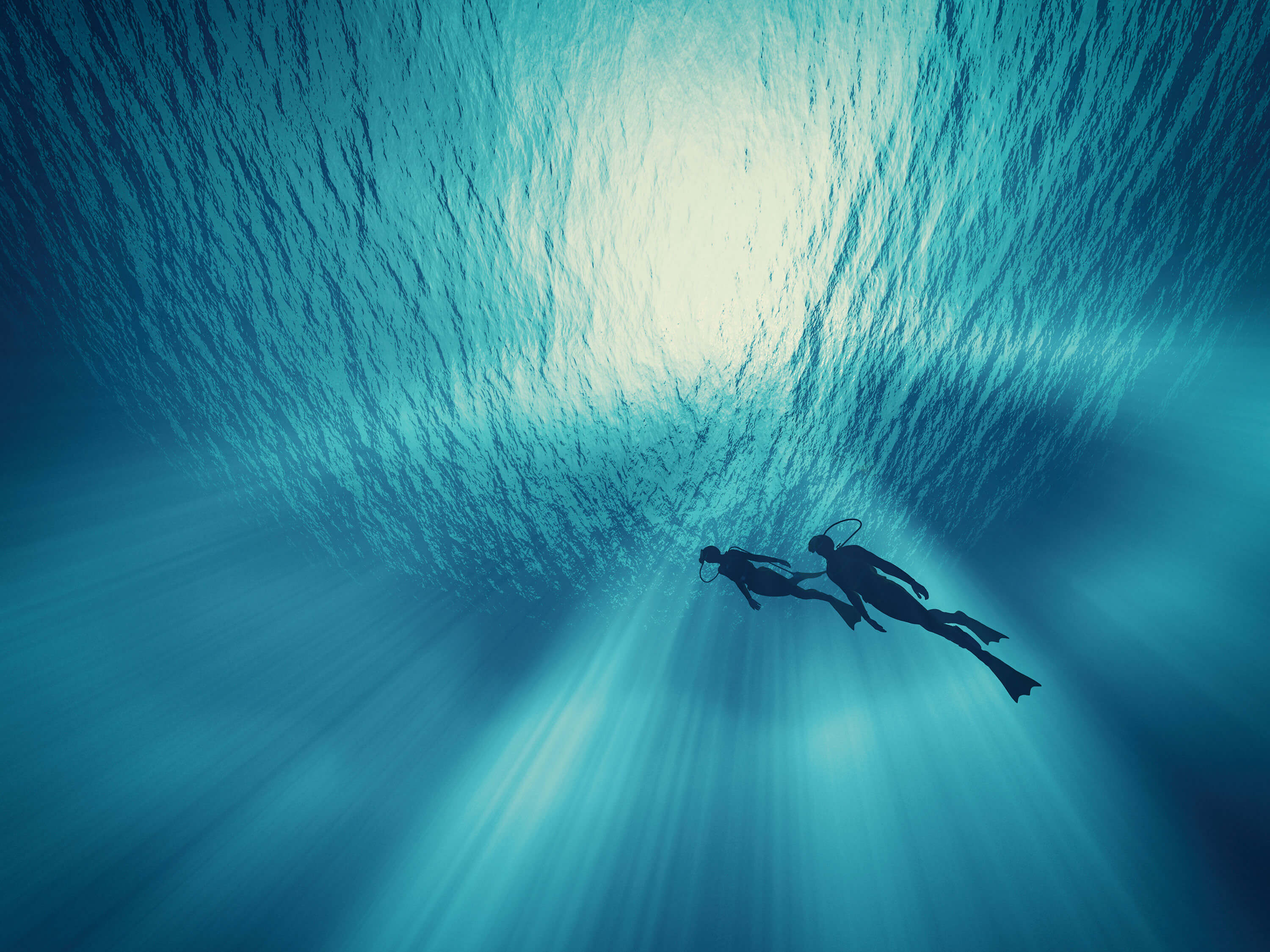 Two scuba divers swimming in blue waters