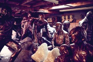 An array of bronze sculptures lit by the floursecent lights of a storage room,