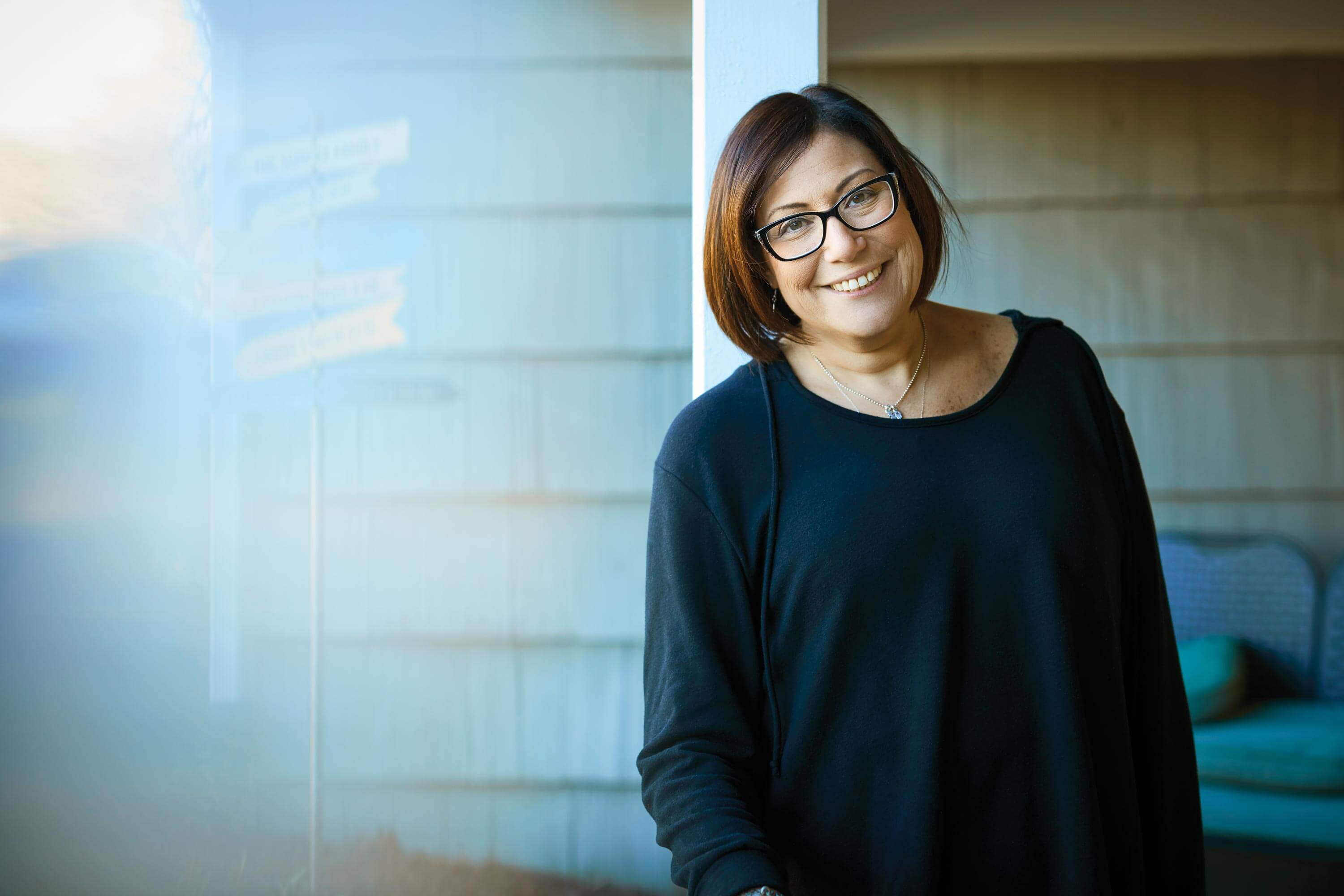 Photograph of Melissa Surdez smiling with a house in the background