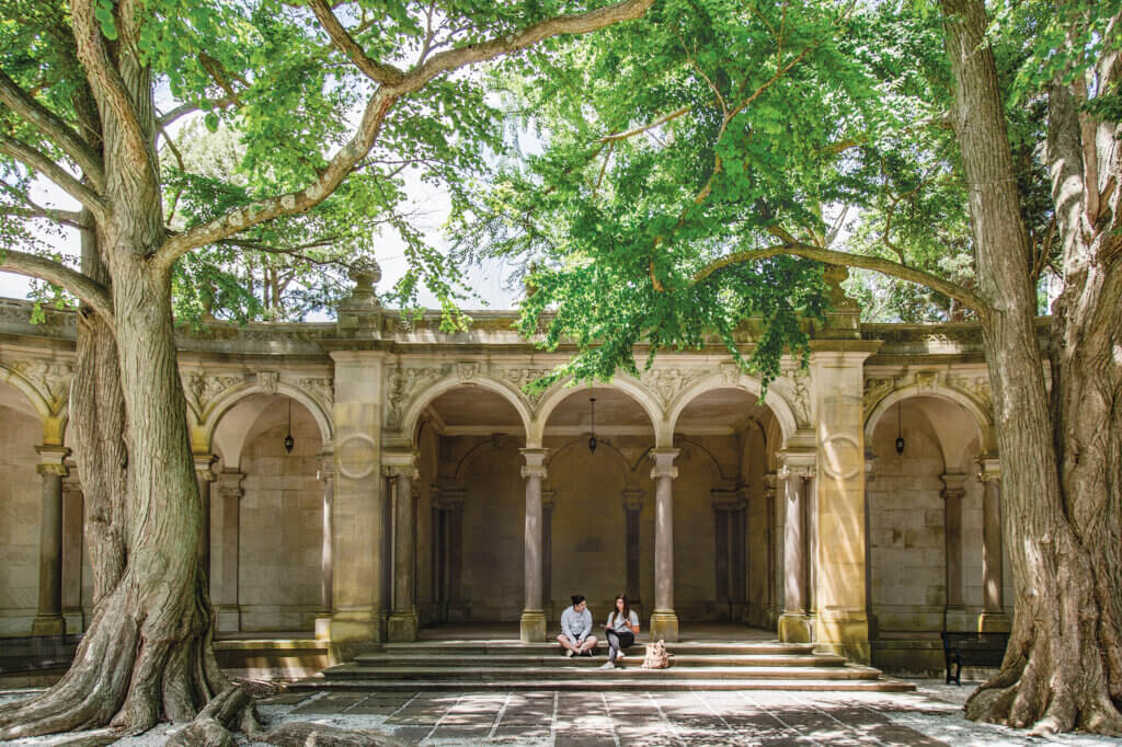 two students sitting under the columns in Erlanger Gardens