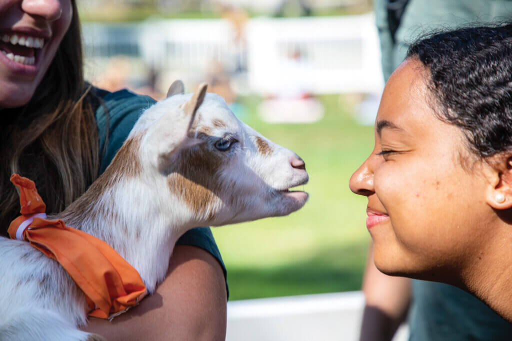 a student face to face with a baby goat