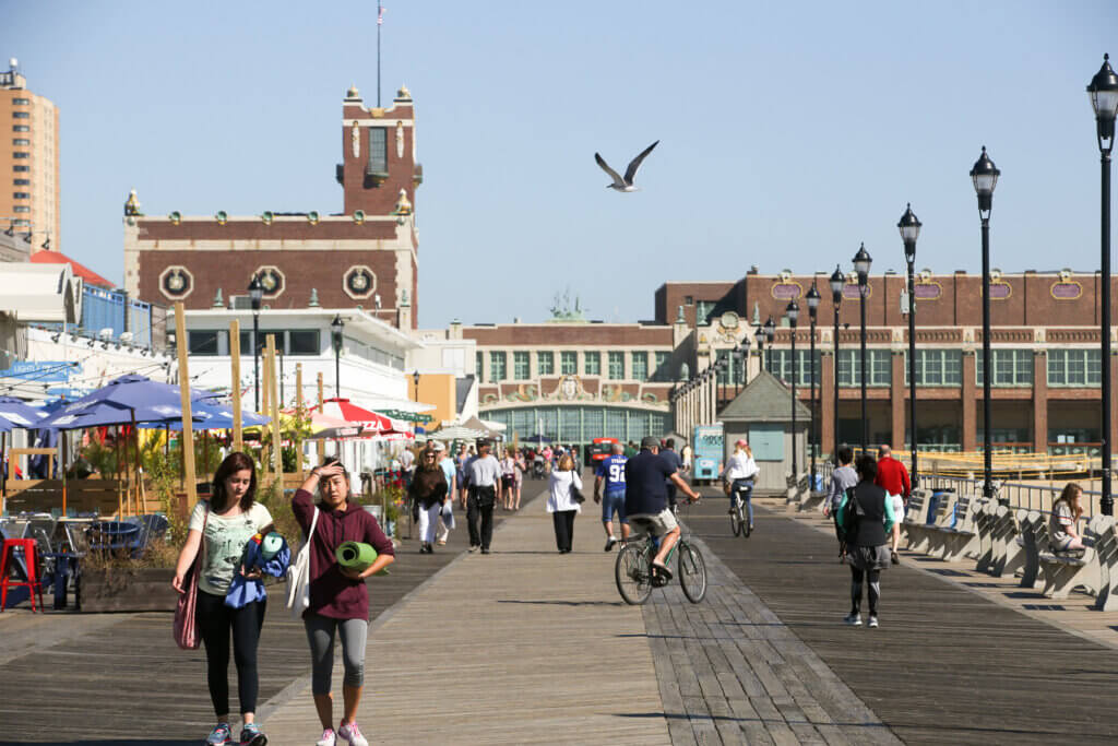 people strolling on the Asbury boardwalk during the day, with Convention Hall in the background