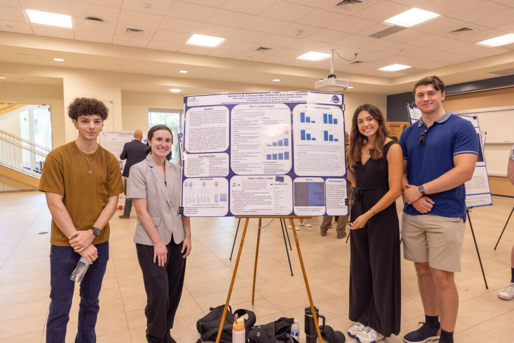 Four Monmouth University students stand beside their research poster on AI-driven sepsis detection