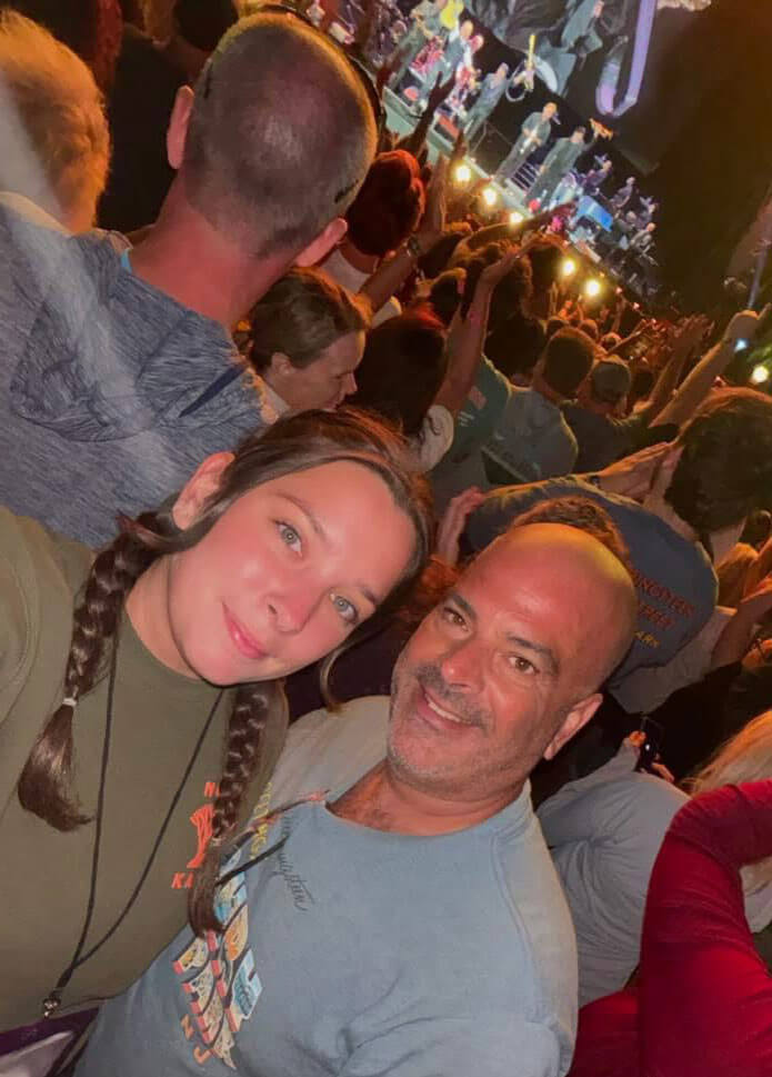 Julian and Abby Garcia pose for a selfie in a crowd at an outdoor concert