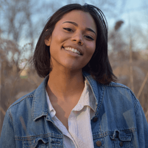 A photo of Sophia Parola standing outside with tall grass behind her in the fall. 