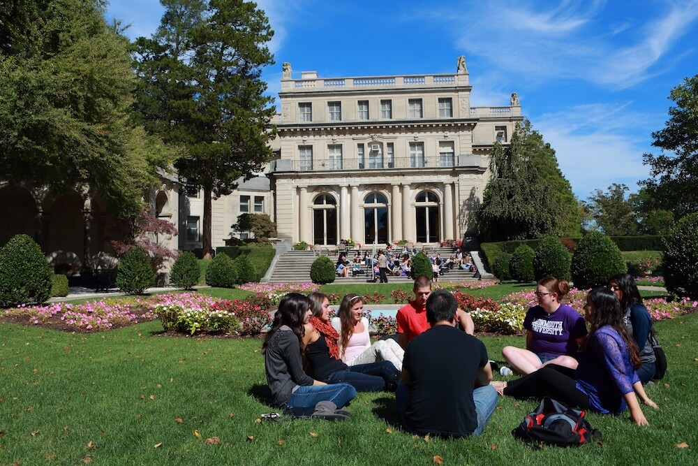 Students sitting in a garden talking with eachother.