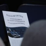 Photo shows audience member reading Waves of Change exhibit flyer