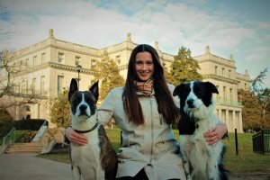 Prof. Mehrkam stands in front of the Great Hall between two black and white dogs