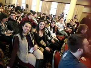 a photo of four people sitting in a crowded conference room