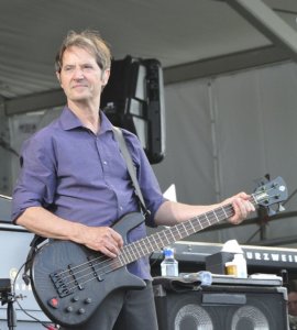 A photo of Garry Tallent playing guitar on a stage. 