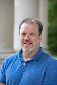 Man wearing blue shirt standing outside. Prof. John Morano