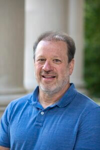 Man wearing blue shirt standing outside. Prof. John Morano