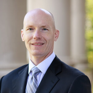 Headshot of Prof. Robert Scott in dark suit and blue tie