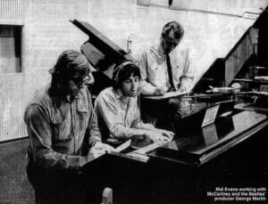 Black and white image of three men sitting at piano (Mall Evans, Paul McCartney, and George Martin)