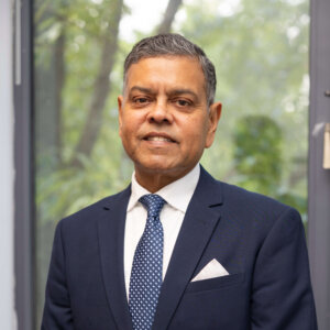 Man in suit and tie standing indoors in front of window