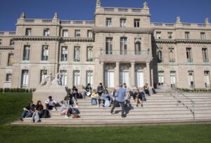 Exterior picture of southern elevation of Great Hall with students taking class outside on stairs