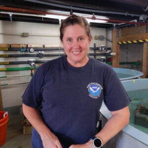 Woman in blue shirt standing in wet lab. Meredith Comi.