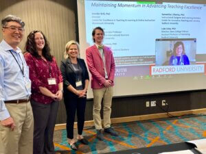 Four faculty members stand in front of presentation projected on to screen.