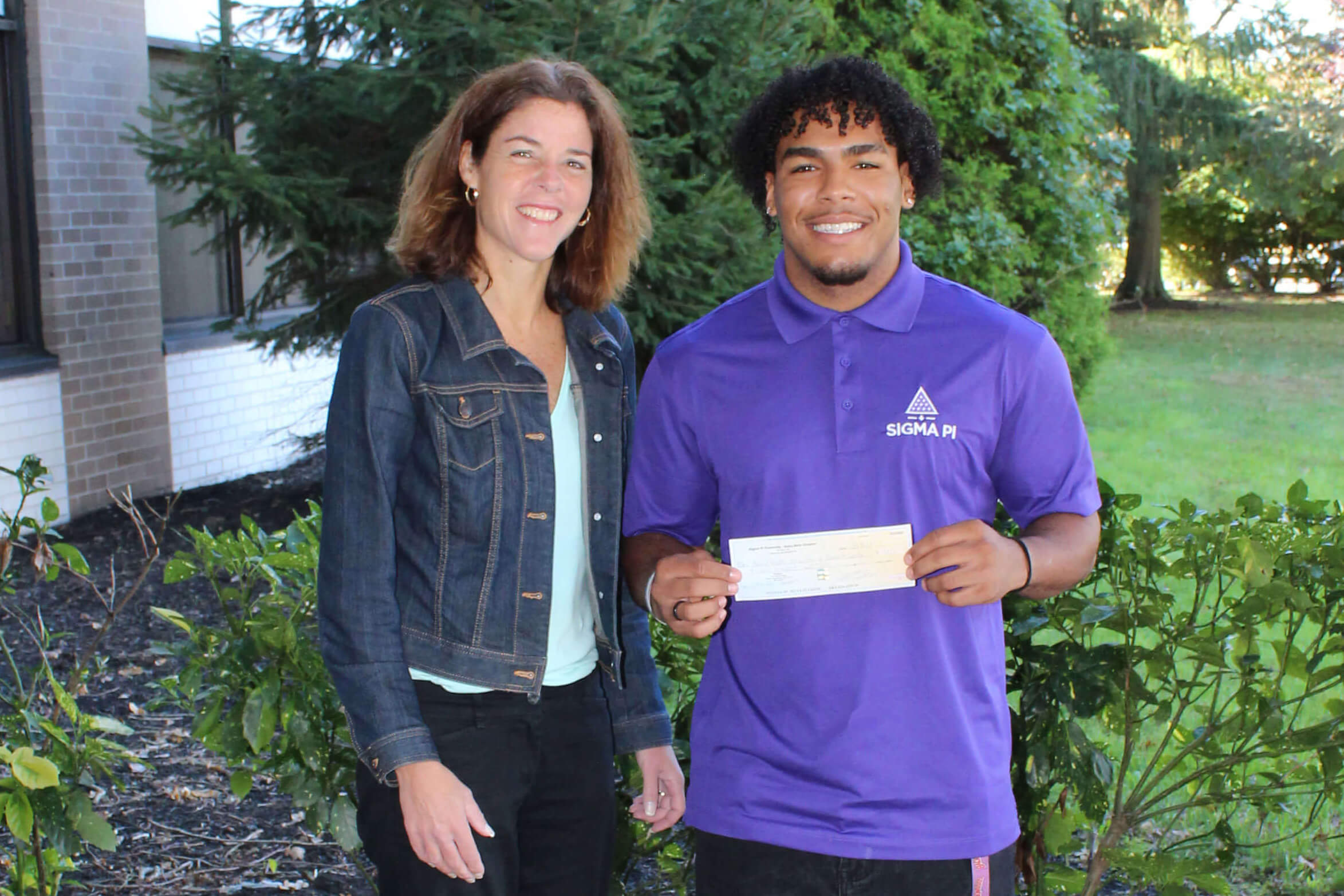 Senior marketing student Isyhne Woodard presents a check to Jeanne Navagh from the Mental Health Association of Monmouth County (MHA).