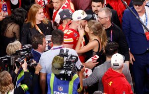 Travis Kelce and Taylor Swift kissing in the middle of a post-Superbowl crowd