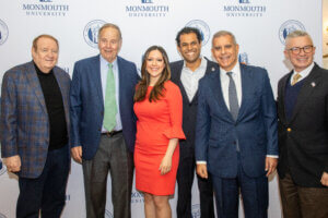Former and current political figures and an award-winning journalist standing in front of a step and repeat for a political discourse event at Monmouth University.