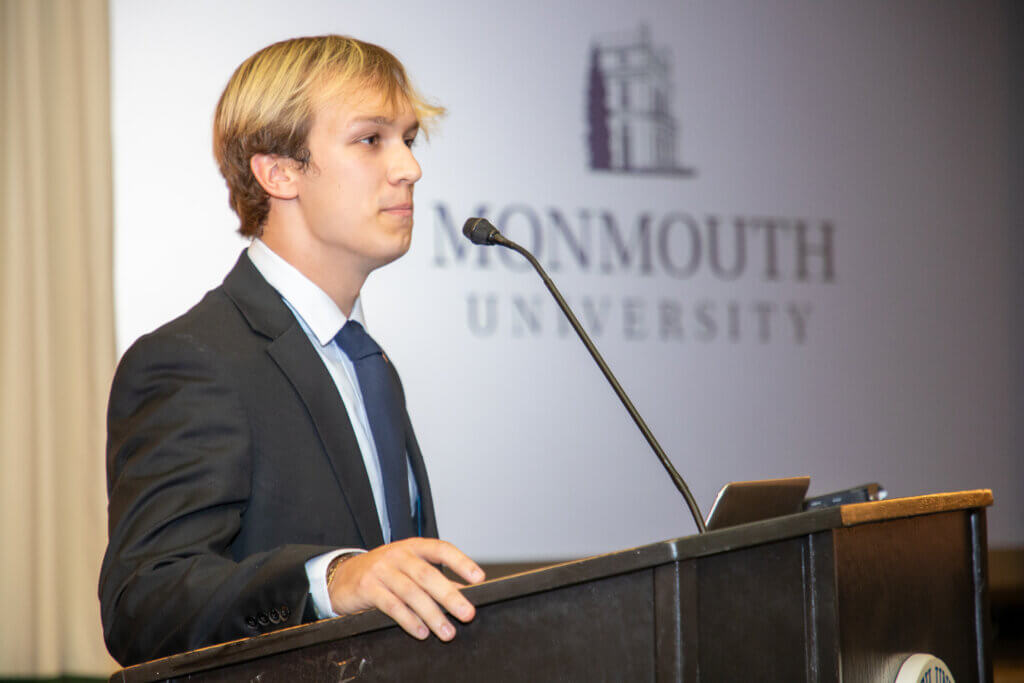 Monmouth University student stands at a podium and gives a speech during an event.