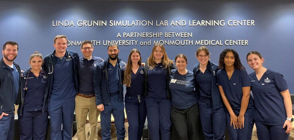 Monmouth University Physician Assistant faculty and students standing in front of the Linda Grunin Simulation Lab and Learning Center sign