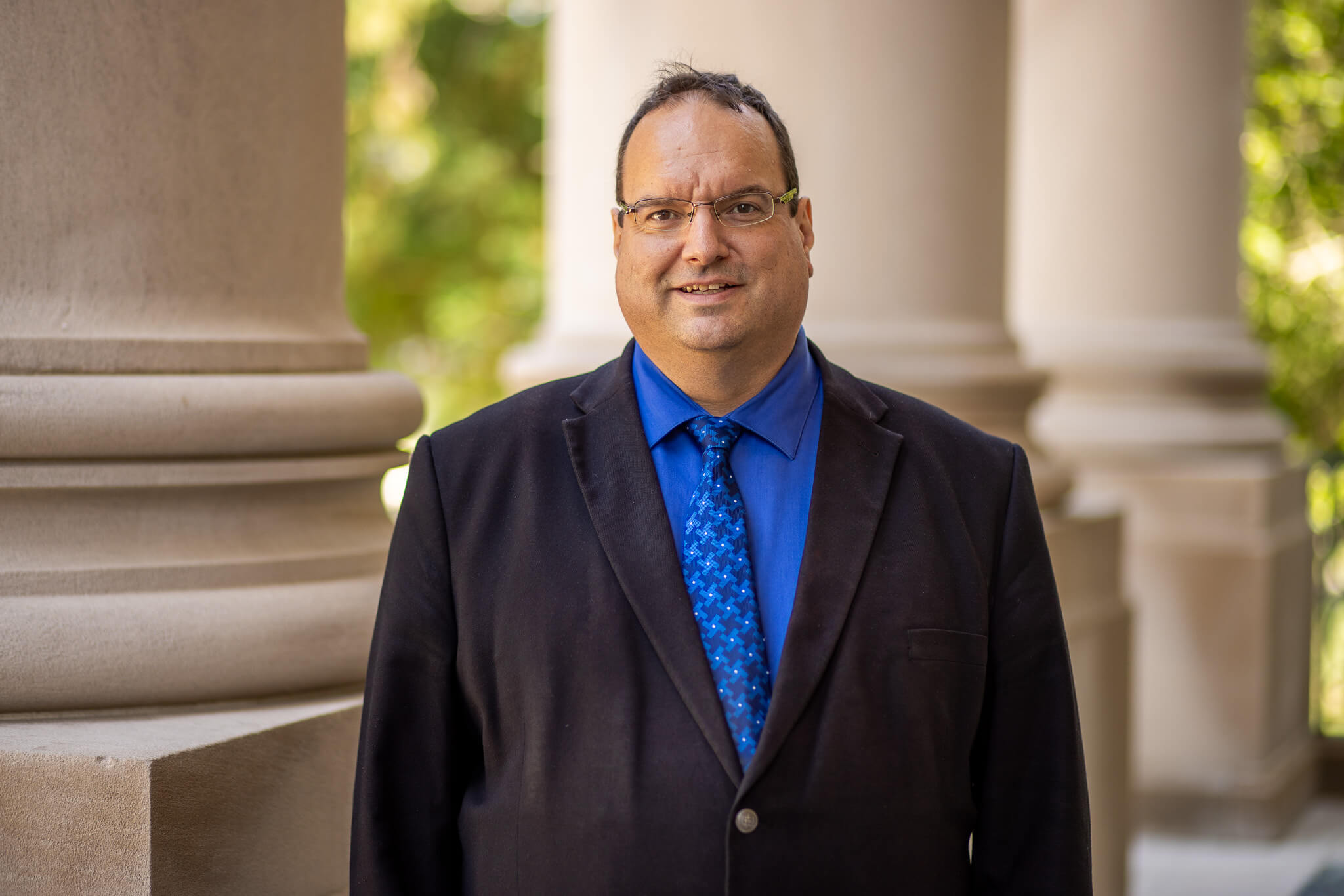 Prof. Jonathan Ouellet standing on porch of Great Hall
