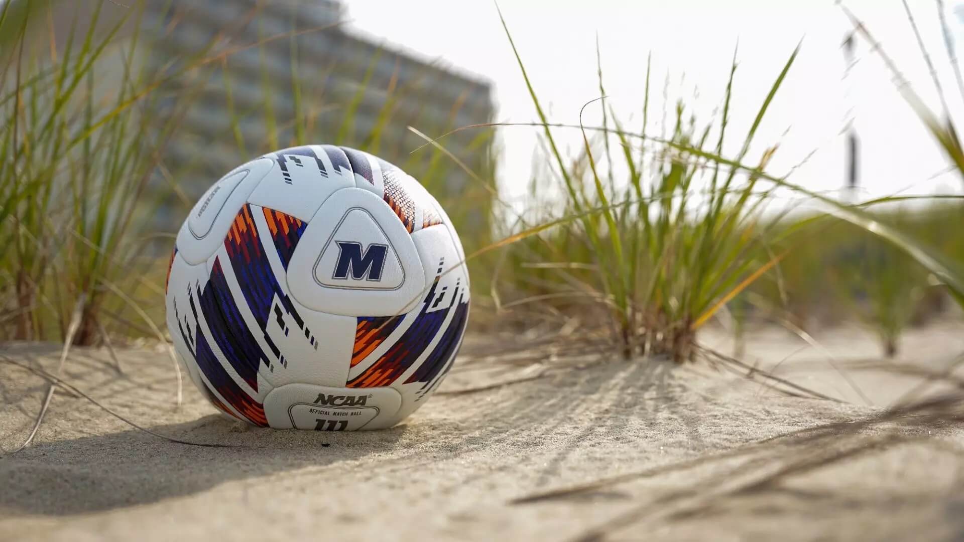 A soccer ball with the Monmouth logo on the beach