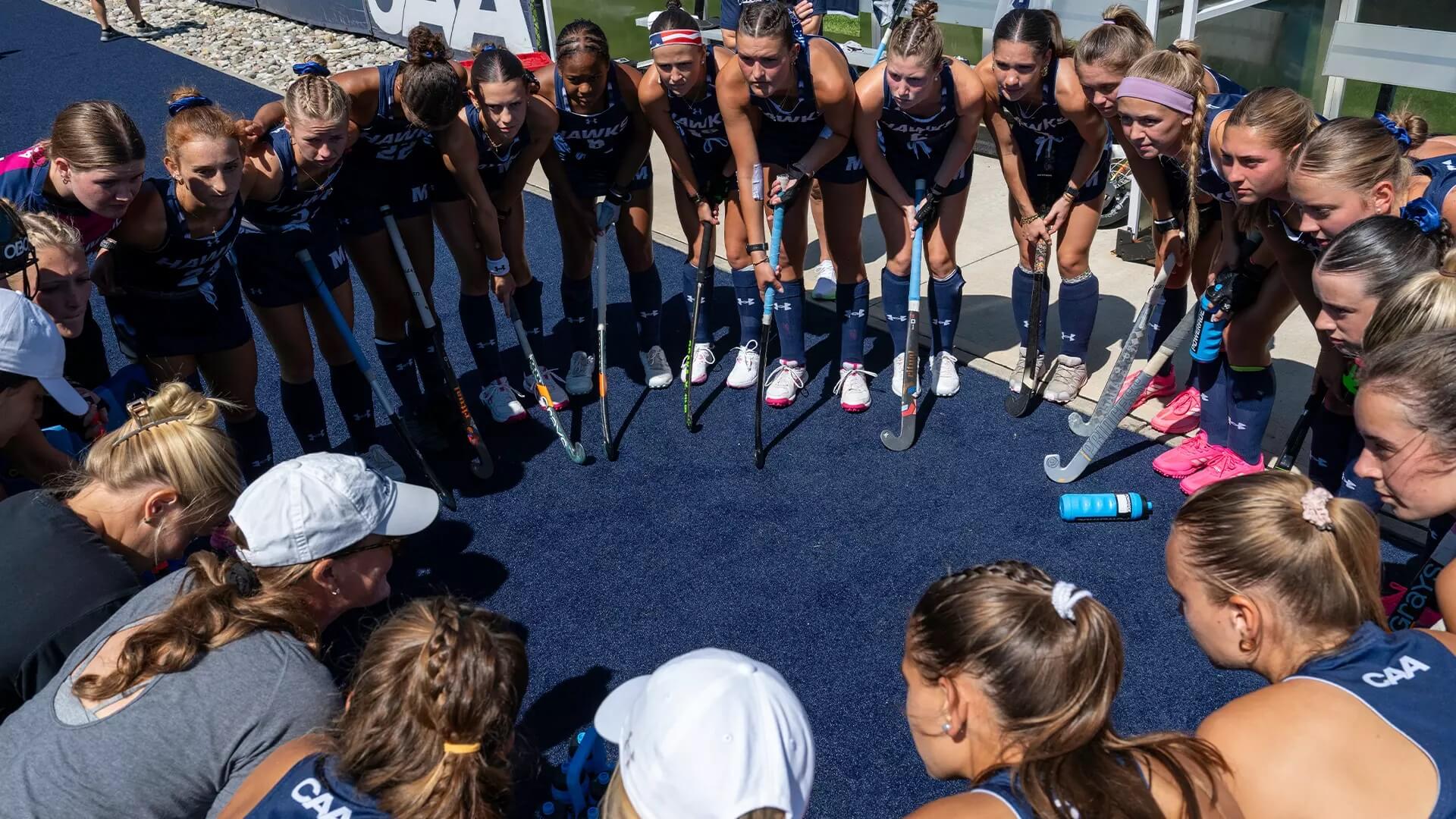 Members of field hockey team prep for game in a circle