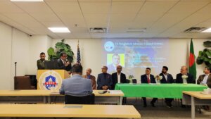 Man at podium adjacent to people seated for panel discussion