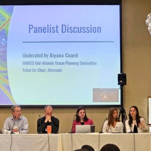 Panelists sit under presentation about marine debris