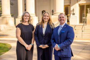 Professor Meg Forney, graduate student Sarah Bilotta, and Professor Douglas Collier pose in front of the Great Hall