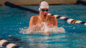 Man swimming in pool with goggles and cap