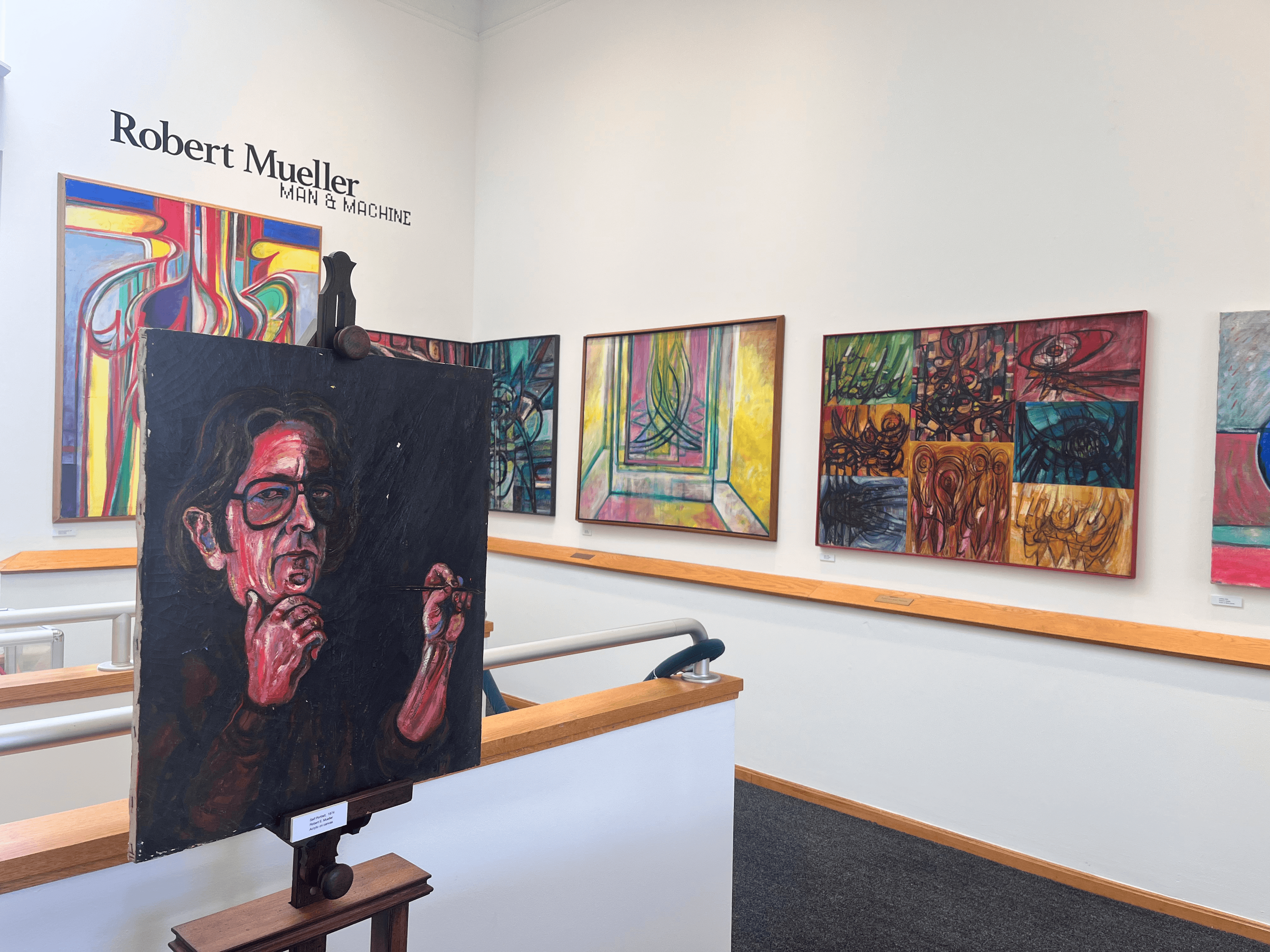 Paintings hang on the wall of an art gallery for the exhibition Robert Mueller: Man & Machine.
