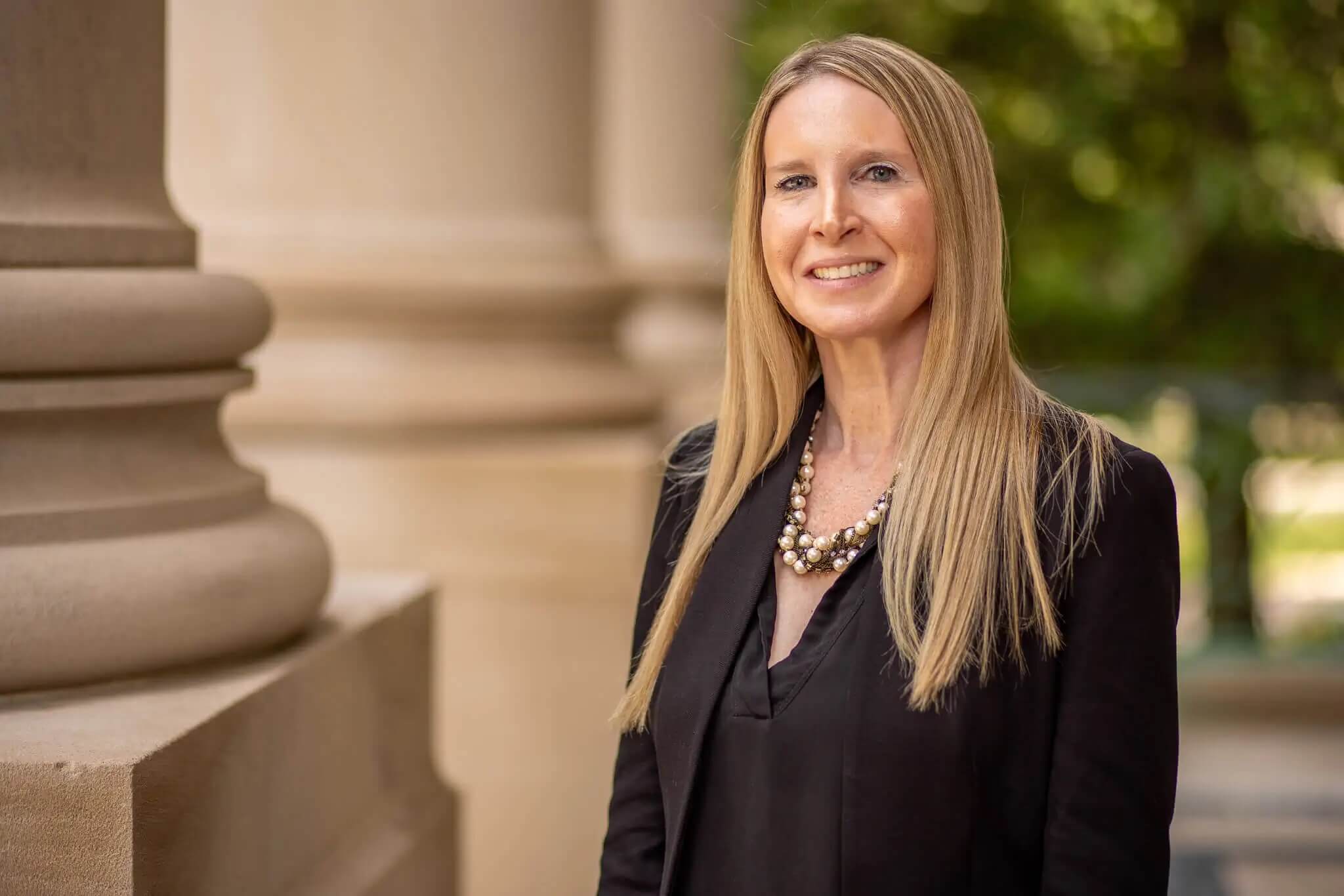 Headshot of Professor Susan Pattay standing in front of the Great Hall