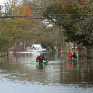 A group of people wading through a flooded street after a storm