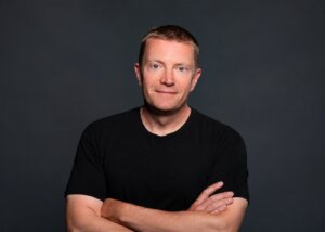 Professor Gary Lewandowski stands with his arms crossed, wearning a black shirt.
