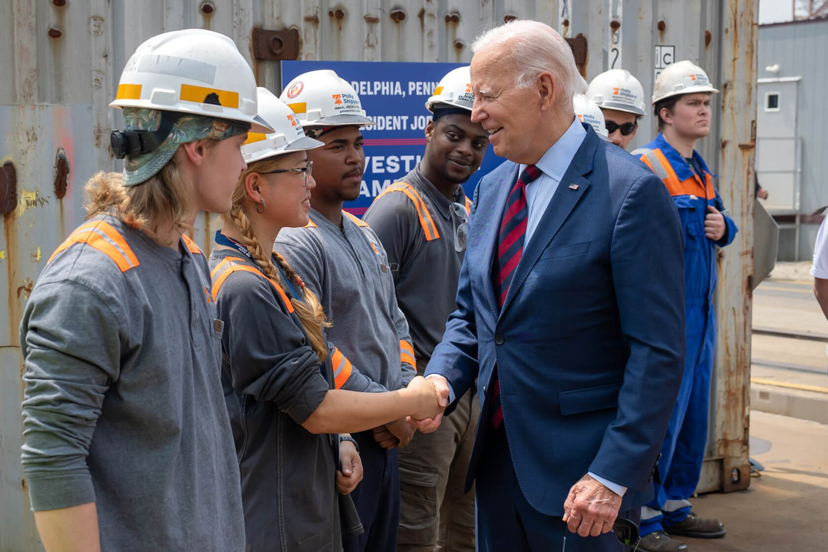 Image of President Biden shaking hands with factory workers.