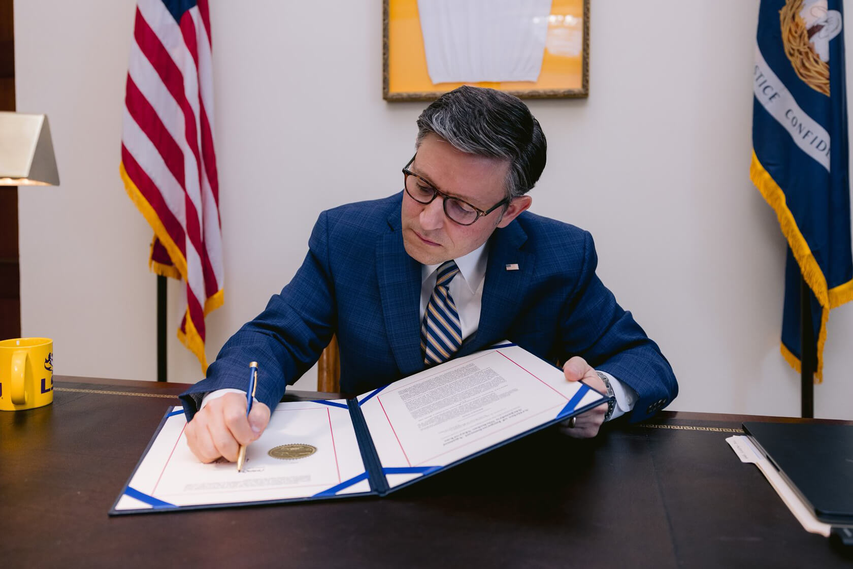 Image of Mike Johnson signing a document.