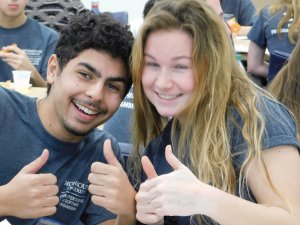 1 male and 1 female student holding their thumbs up and smiling