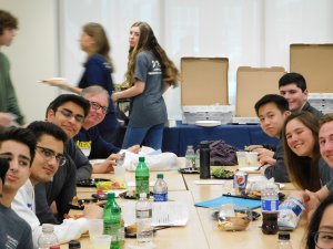 Group of male and female students and teachers eating lunch together and smiling