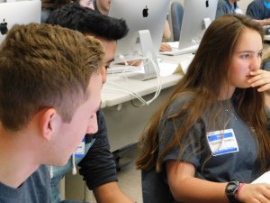 2 male students with 1 female student to their right working on their programs