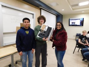 3 students (2 males and 1 female) holding up a 3D printer they each won for 1st place in the Monmouth University High School Programming Contest