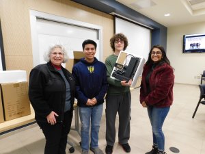 3 students (2 males and 1 female) with MU Professor Kretsch holding up a 3D printer they each won for 1st place in the Monmouth University High School Programming Contest