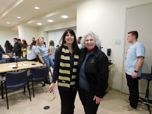 MU Professor Kretsch standing with Ms. Corrado from Toms River and smiling as male and female students move in the background