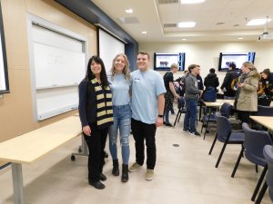 2 Monmouth University student volunteers, 1 a male and 1 a female smiling and standing alongside their female teacher from Toms River North high school Ms. Corrado