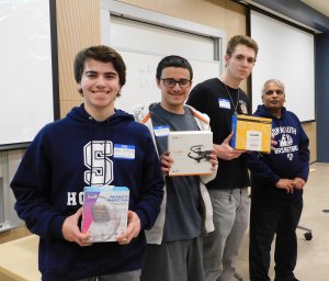 3 male students and sponsor Dr. Lakshmanan. Students are holding prizes won for 3rd place in Monmouth University High School Programming contest 2019