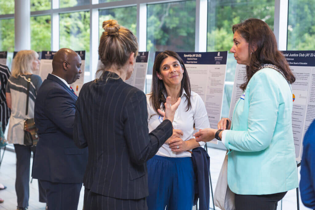 Professionals having a conversation with poster presentations in the background